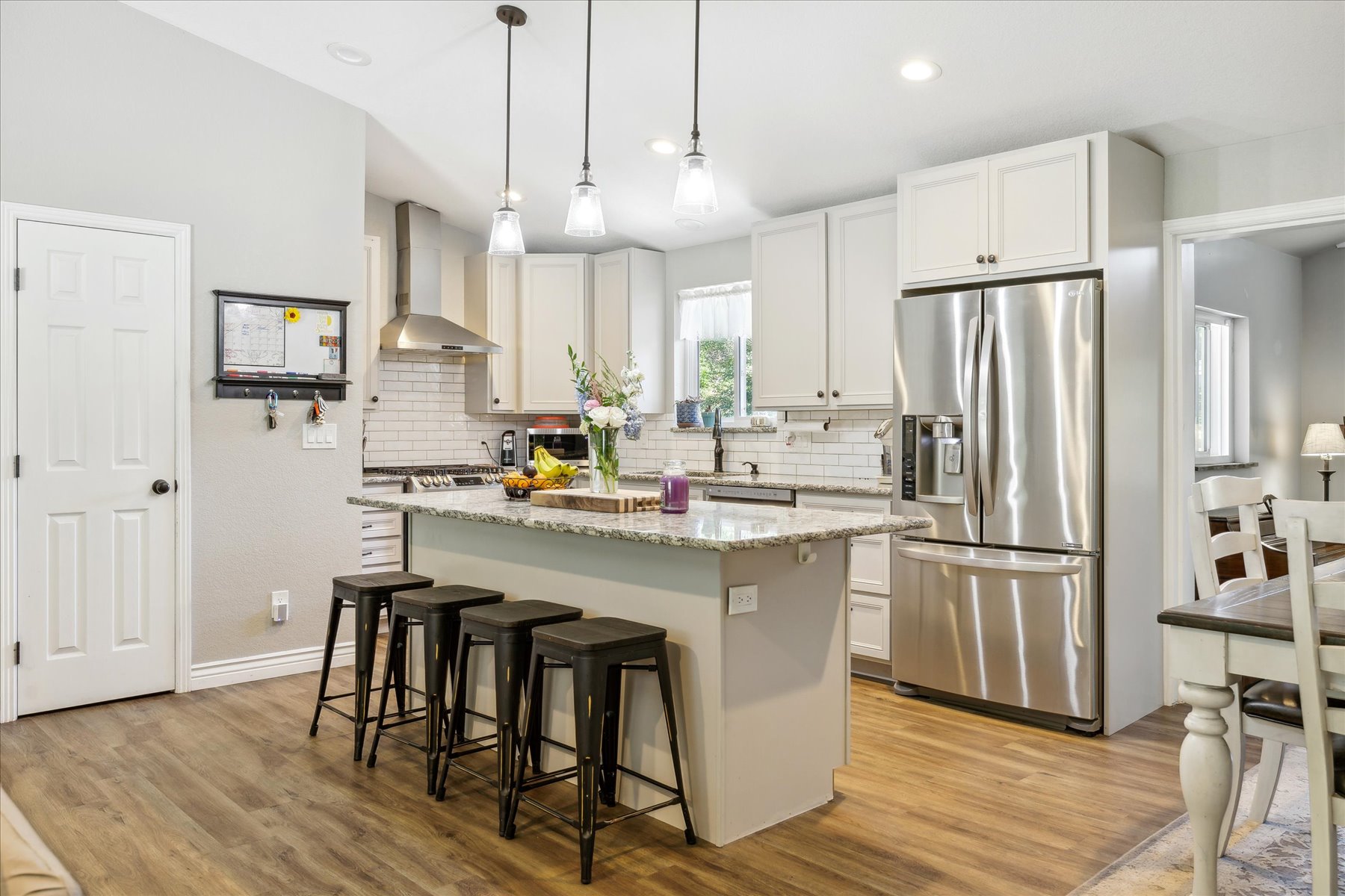 Bright kitchen with white cabinets, large island and black bar stools