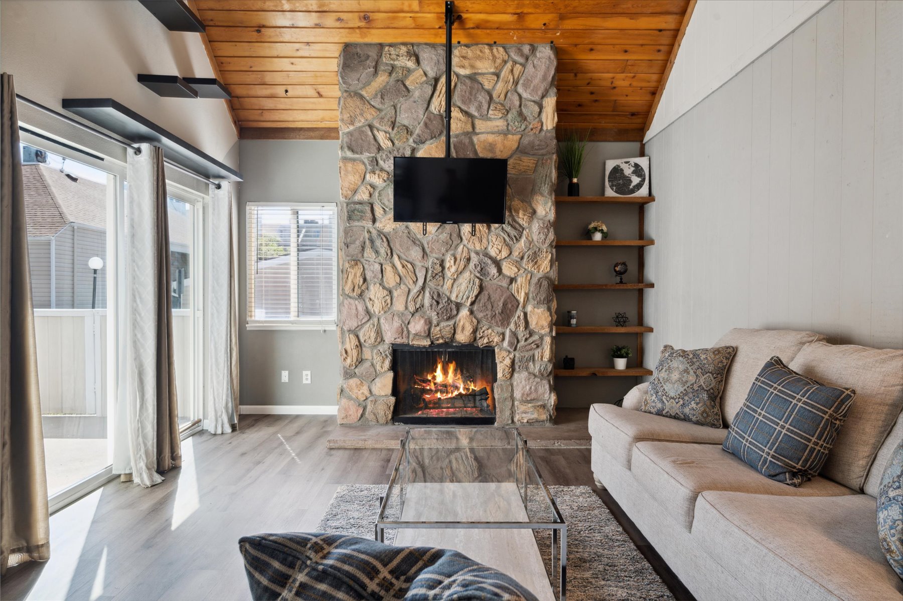 Living room with a stone fireplace and wood ceiling